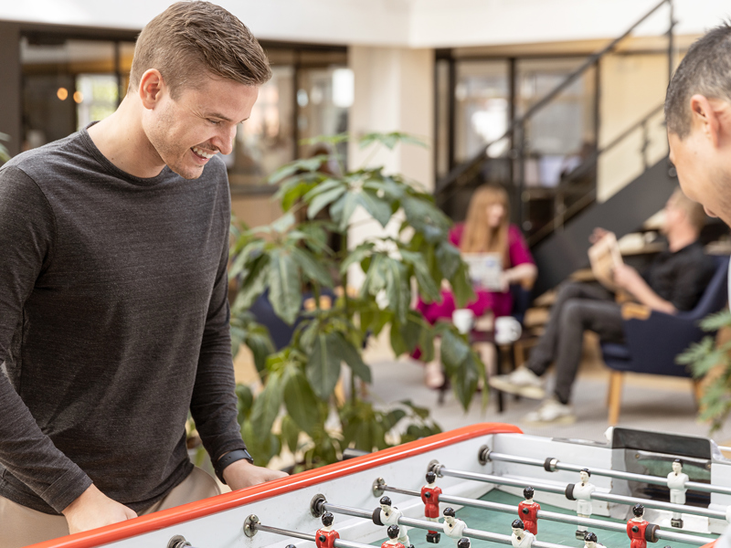 Mand i graa troeje spiller bordfodbold