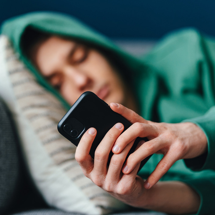 Ung Mand Tjekker Telefon I Sofa