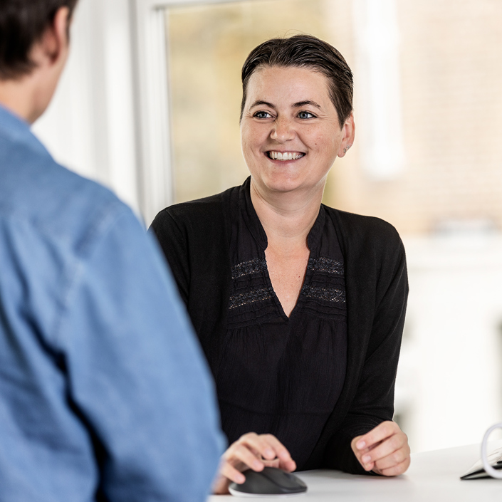 Kvinde og mand samtaler foran PC