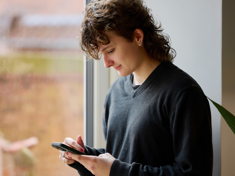 Kvinde Med Telefon Foran Vindue